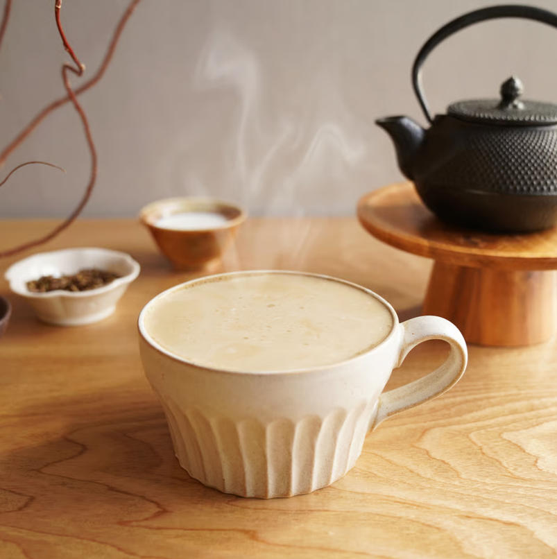 焙茶拿鐵沖泡情境，白色杯中的飲品搭配日式茶壺與茶點